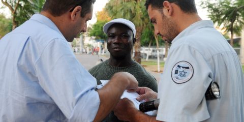 An African talking with police officers in Tel Aviv.