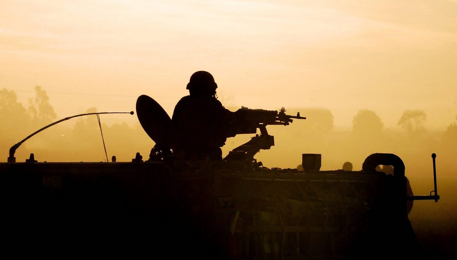 Silhouette of an army soldier preparing his tank and weapons at sunset