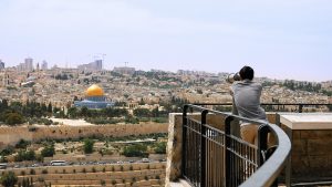 Jerusalem, Israel - May 25, 2017: Tourist looks in binoculars tower viewer at the Jerusalem Old City view. Mount of Olives is a famous Holy Land place and it has a fantastic view to the Old Jerusalem