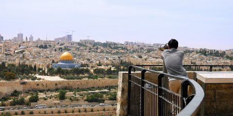 Jerusalem, Israel - May 25, 2017: Tourist looks in binoculars tower viewer at the Jerusalem Old City view. Mount of Olives is a famous Holy Land place and it has a fantastic view to the Old Jerusalem