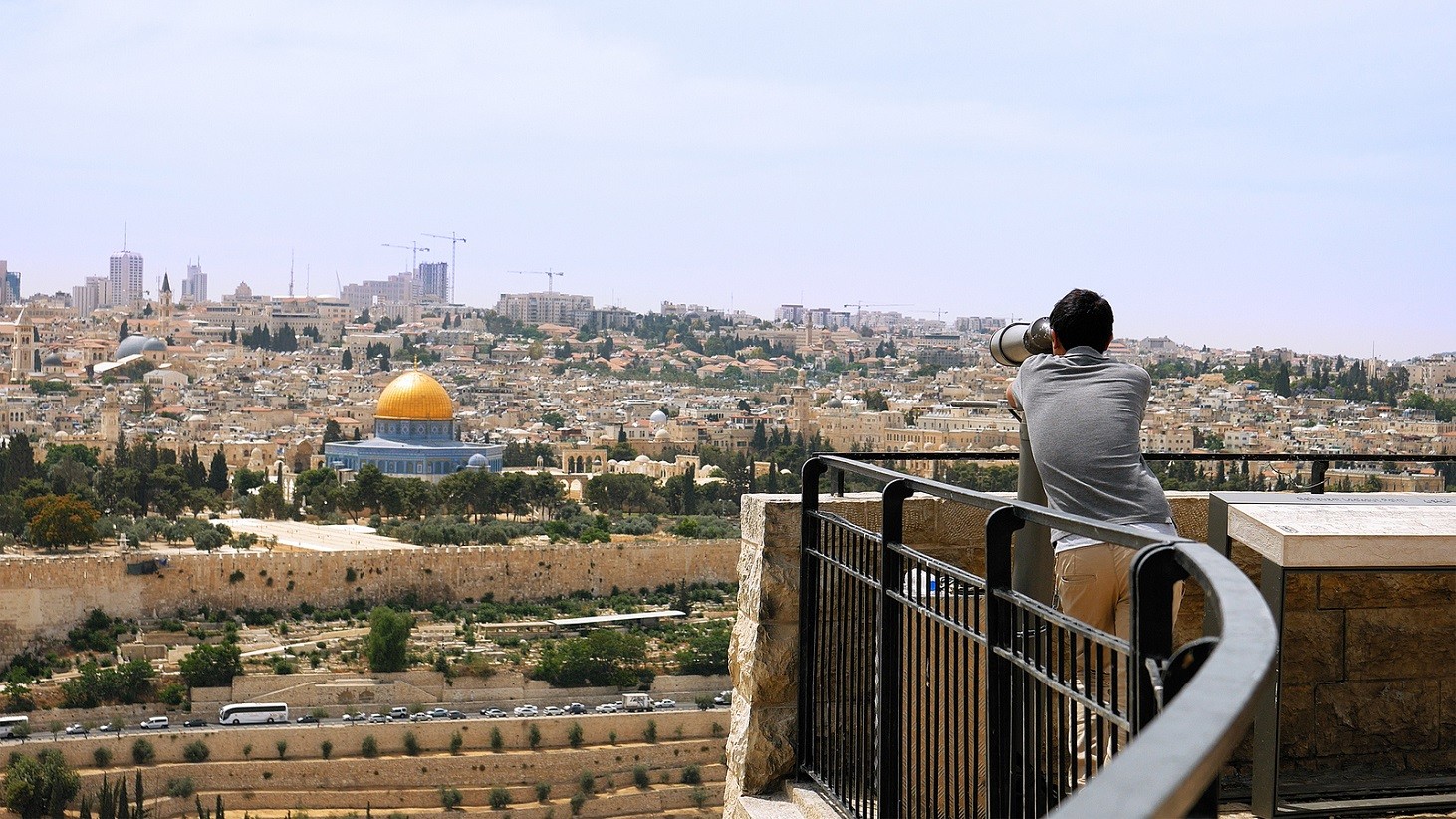 Jerusalem, Israel - May 25, 2017: Tourist looks in binoculars tower viewer at the Jerusalem Old City view. Mount of Olives is a famous Holy Land place and it has a fantastic view to the Old Jerusalem
