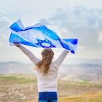 Little patriot jewish girl standing and enjoying with the flag of Israel on blue sky background.Memorial day-Yom Hazikaron, Patriotic holiday Independence day Israel - Yom Haatzmaut concept