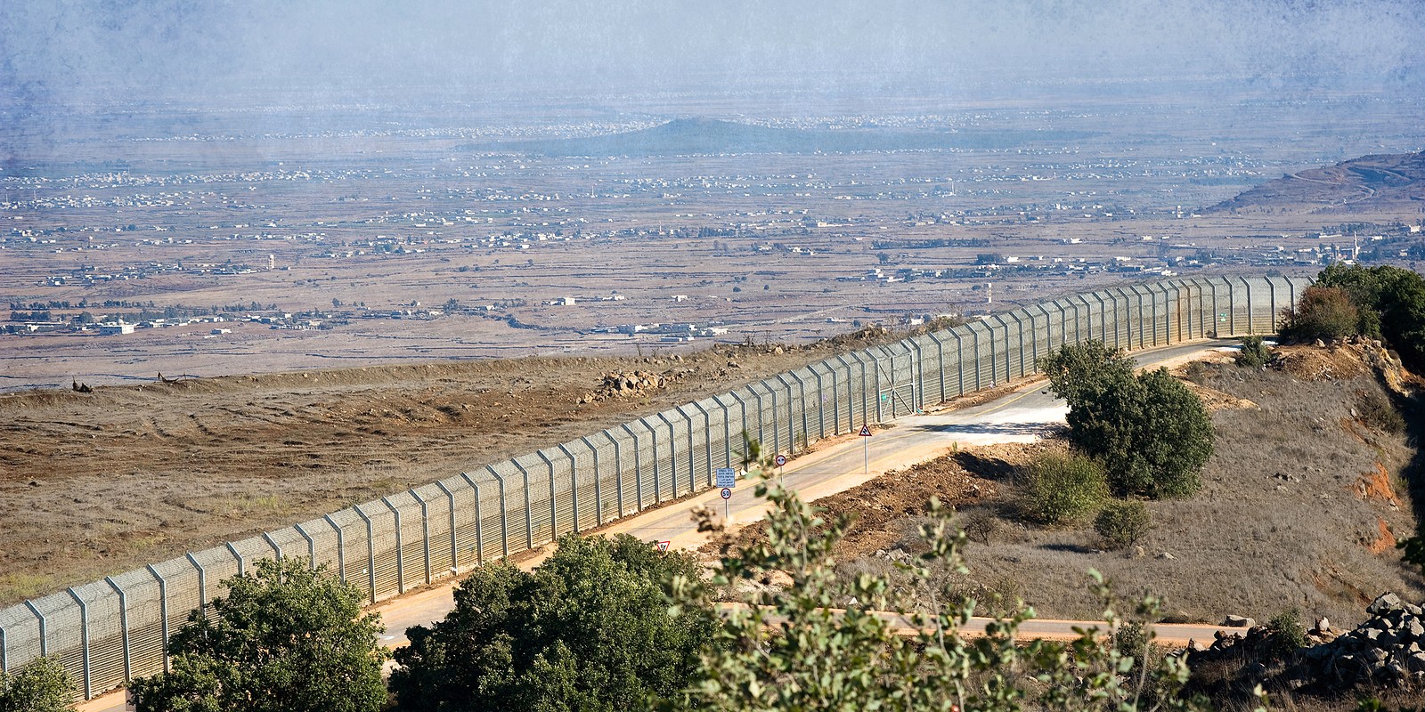 The fence of the border between Israel and Syria as seen from a hill on the Golan Heights about 10 kilometers south/south-east of the city Al Quneitra
