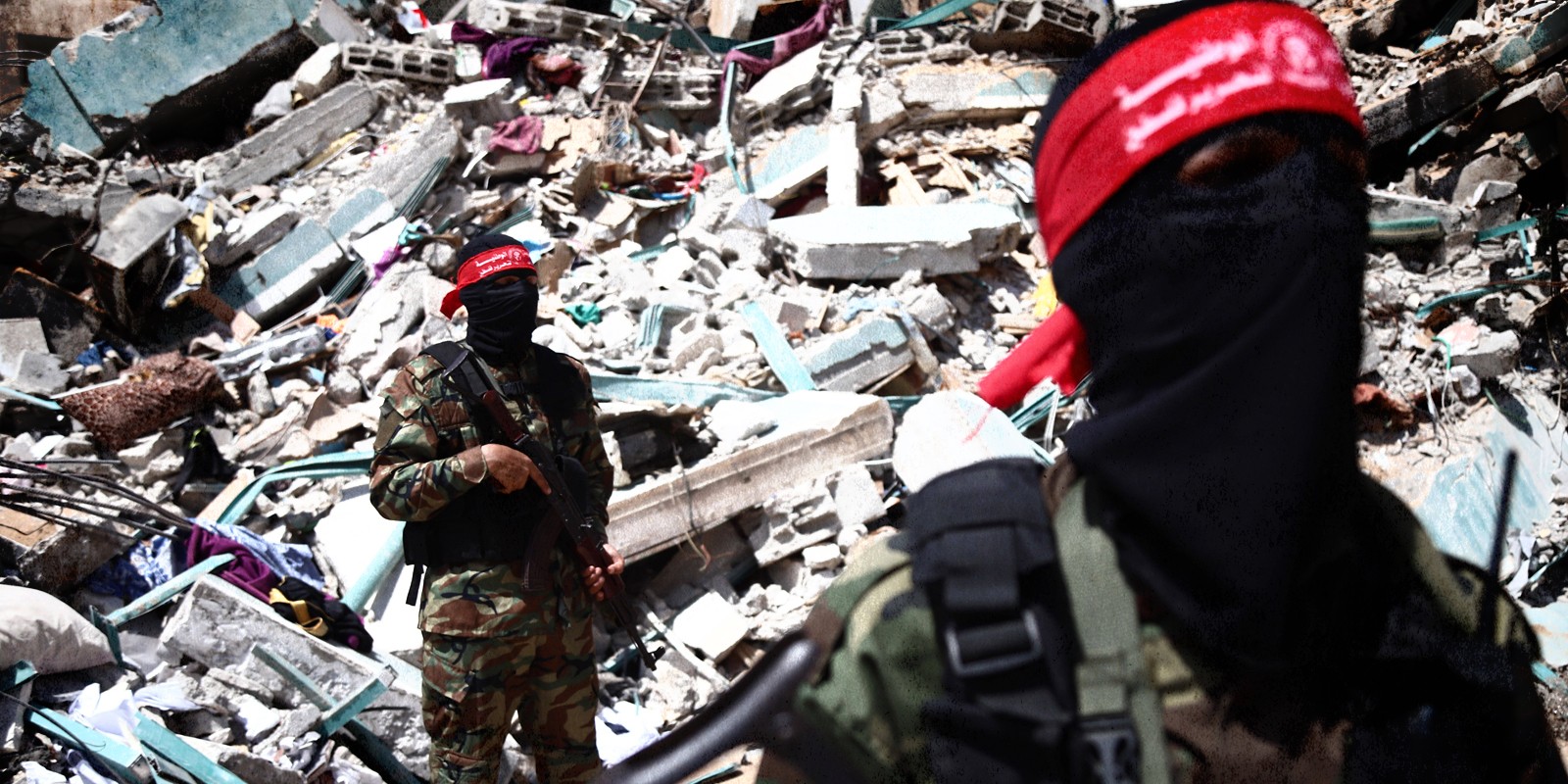 Palestinian militants stand in front of a crashed building