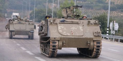 Israeli soldiers in an armoured vehicles drive along a street near northern town of Kiryat Shmona close