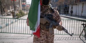 A member of the Islamic Revolutionary Guard Corps (IRGC) holds an AK-45 rifle and stands guard outside a police facility that is destroyed during a U.S.-Israeli military campaign in Tehran, Iran, on March 4, 2026.