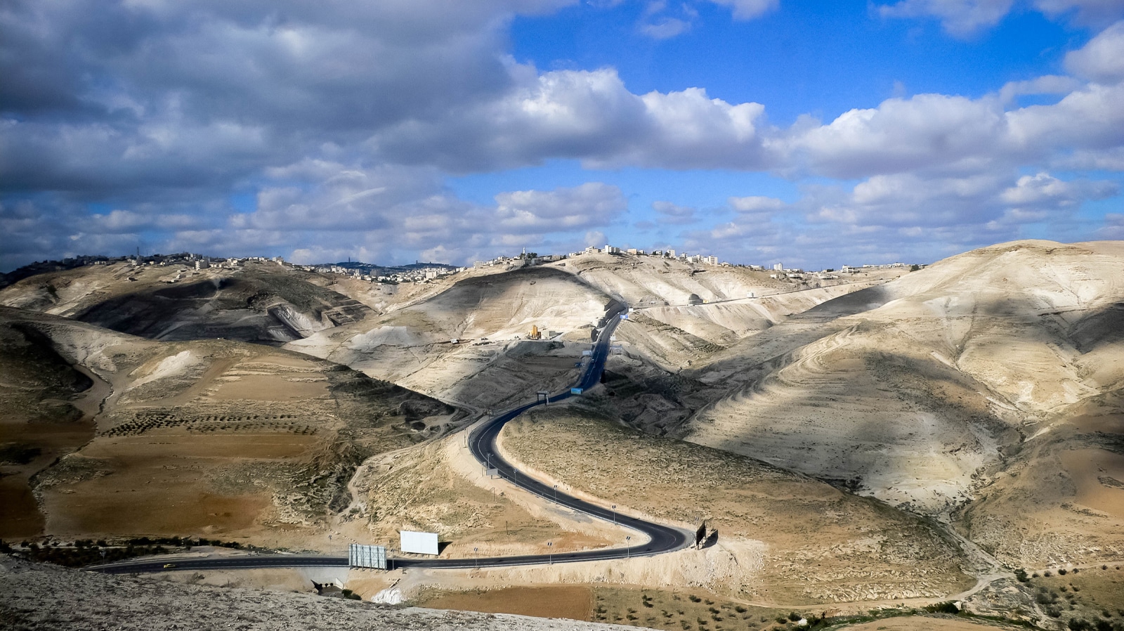 The road into Jerusalem across desert hills under sky and clouds