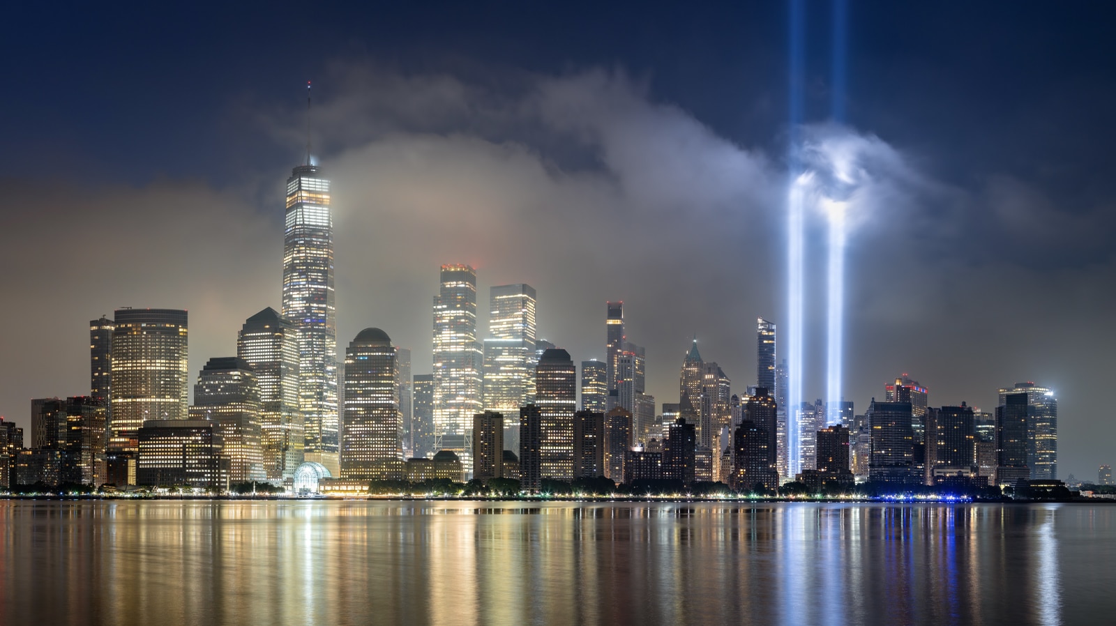 New York City, NY, USA - September 09, 2024: Dawn in Lower Manhattan with skyscrapers and low clouds and the September 11 Tribute in Light memorial lights
